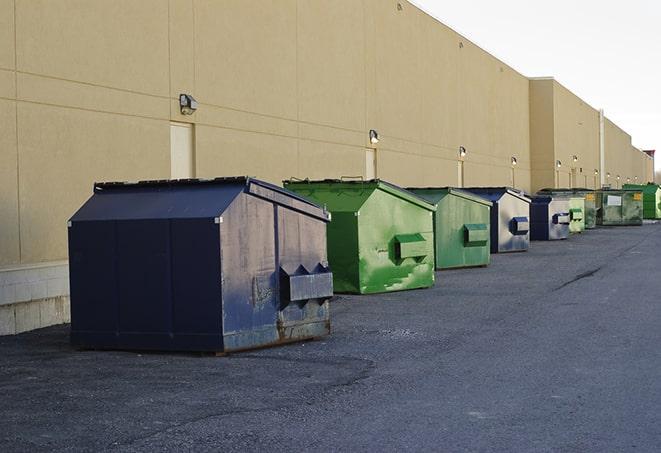 a row of blue construction dumpsters on a job site in Alexander, NC